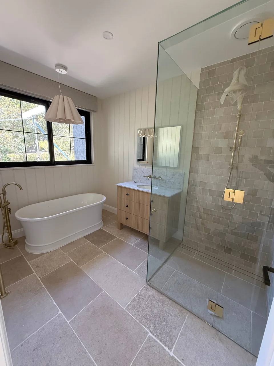Bathroom with freestanding bath, glass shower and brass fittings