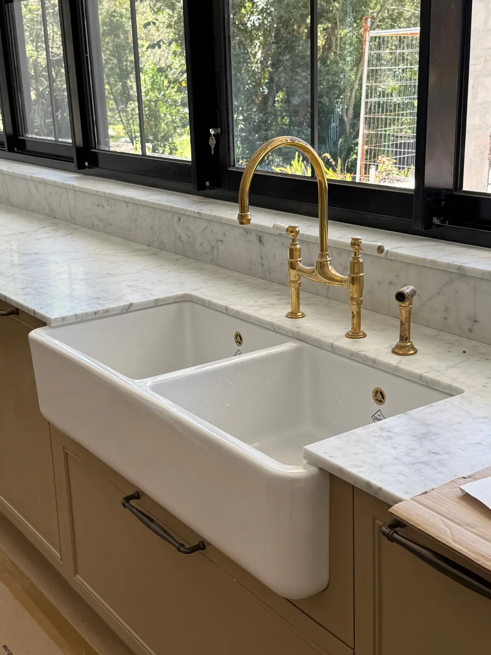 Double ceramic kitchen sink with brass tapware and a marble benchtop