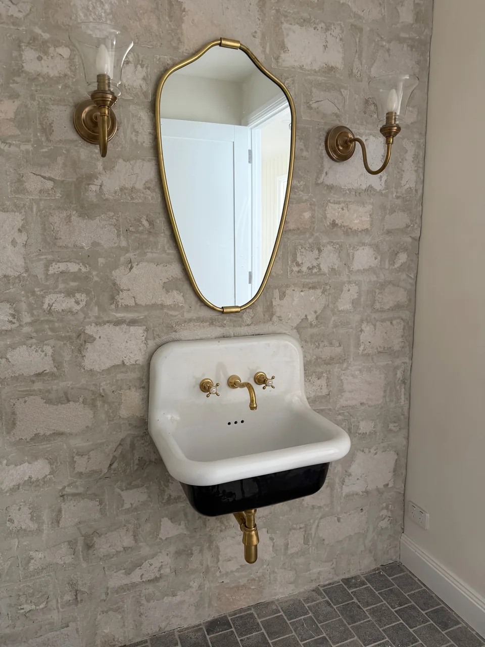 Wall-mounted powder-room basin with brass taps and exposed brass waste pipe